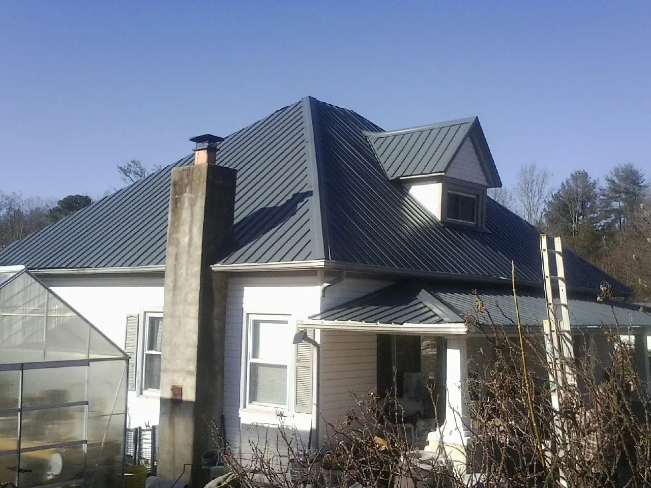 Dark blue standing seam metal roof on a white farmhouse with dormer — Slate & Tile Roof Repair by Roofing Brothers in Otis Orchards