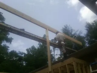 Carpenter setting a ridge beam over a new addition frame — Ice Dam Removal by Roofing Brothers in Otis Orchards