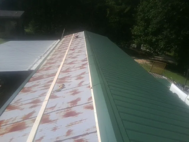 Old rusted panels beside newly installed green metal roofing — Wind Damage Roof Repair by Roofing Brothers in Otis Orchards