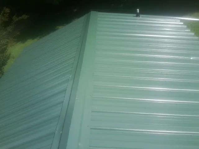 New green metal panels meeting at the ridge of a roof — Flat Roof Repair work by our crew in Otis Orchards