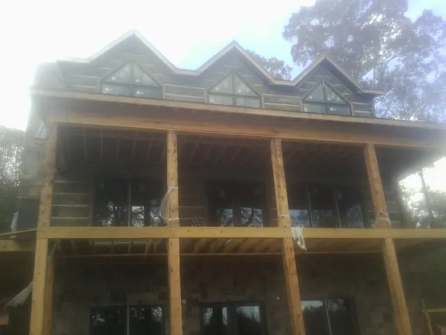 Dormers and porch framing on a large log home under construction — Roof Coating work by our crew in Otis Orchards