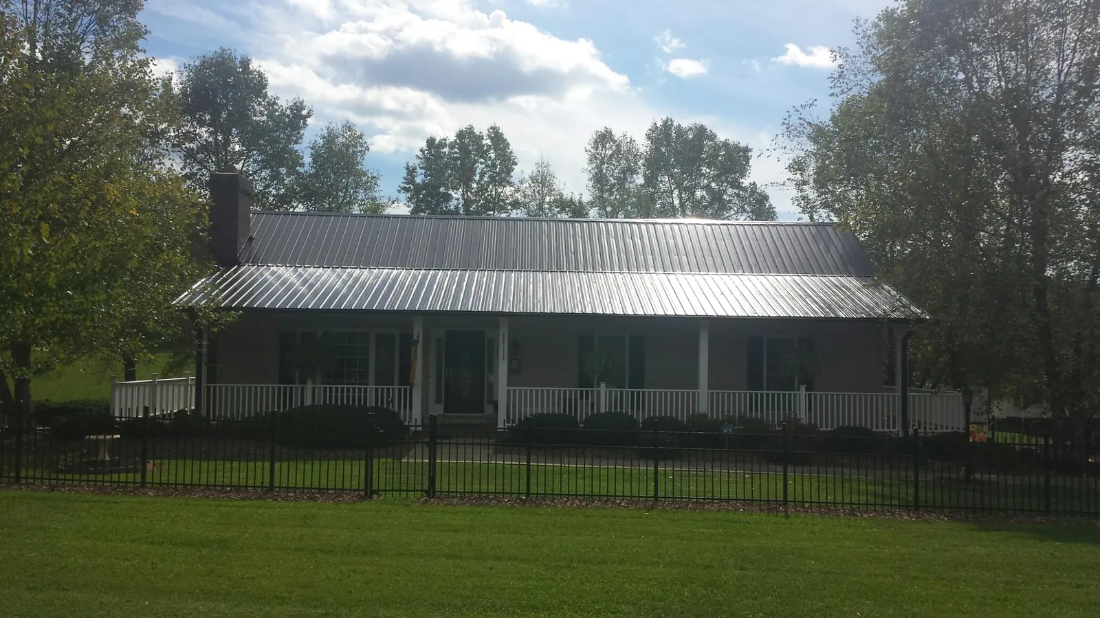 Gray metal roof on a brick ranch with a full width front porch — Gutter Guard Installation work by our crew in Otis Orchards