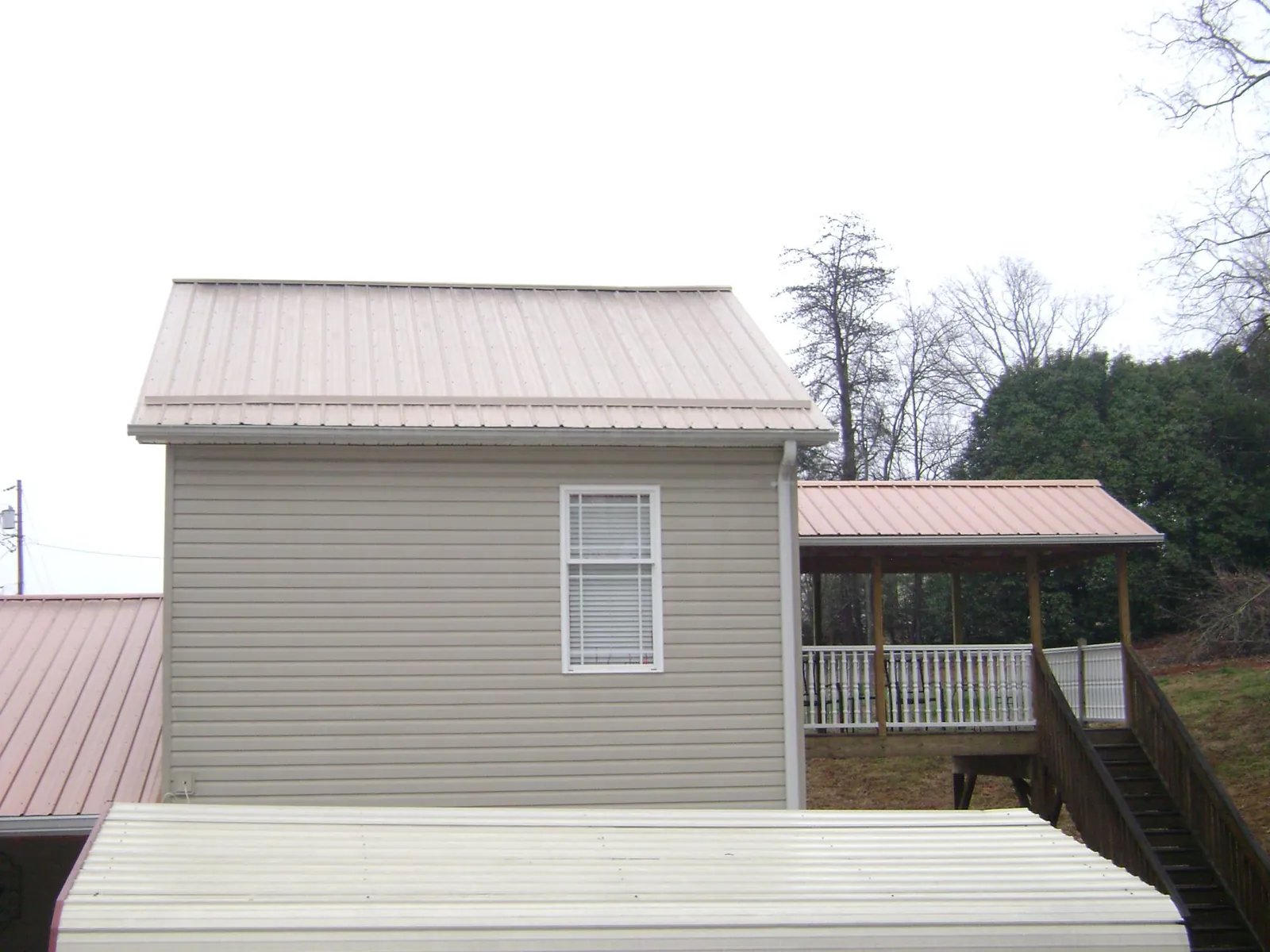 Tan metal roofs on a two story addition and attached porch, from a Roof Replacement job in Otis Orchards