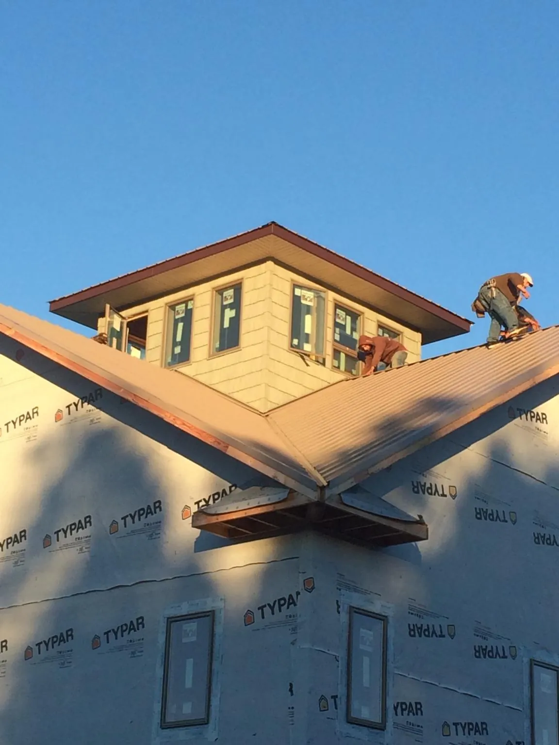 Roofers working around a rooftop cupola on a new metal roof at sunset — Roof Waterproofing in Otis Orchards by Roofing Brothers